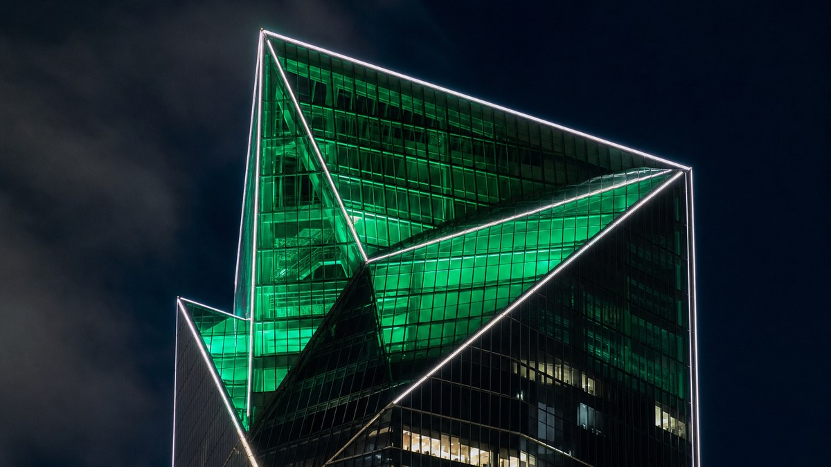 Skyscraper crown with color-changing LED lighting glowing emerald green and white edge lines against a night sky over Dallas